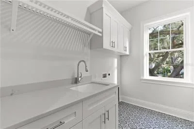 White laundry room with custom cabinetry, sink, terrazzo flooring, and subway tile backsplash