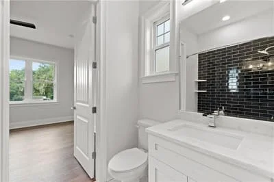 Modern bathroom with white vanity, black subway tile backsplash, and recessed lighting
