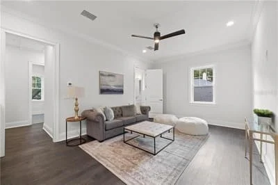 Bright living room with white trim, dark hardwood floors, ceiling fan, and recessed lighting