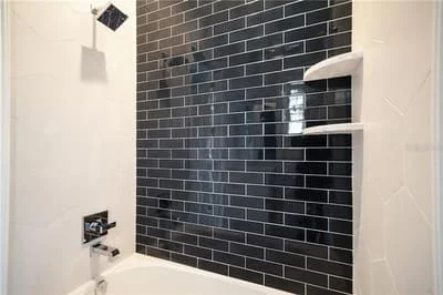 Black subway tile shower wall with recessed shelving and chrome fixtures